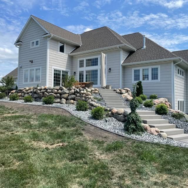 Finished boulder wall and stone steps in a sloped yard