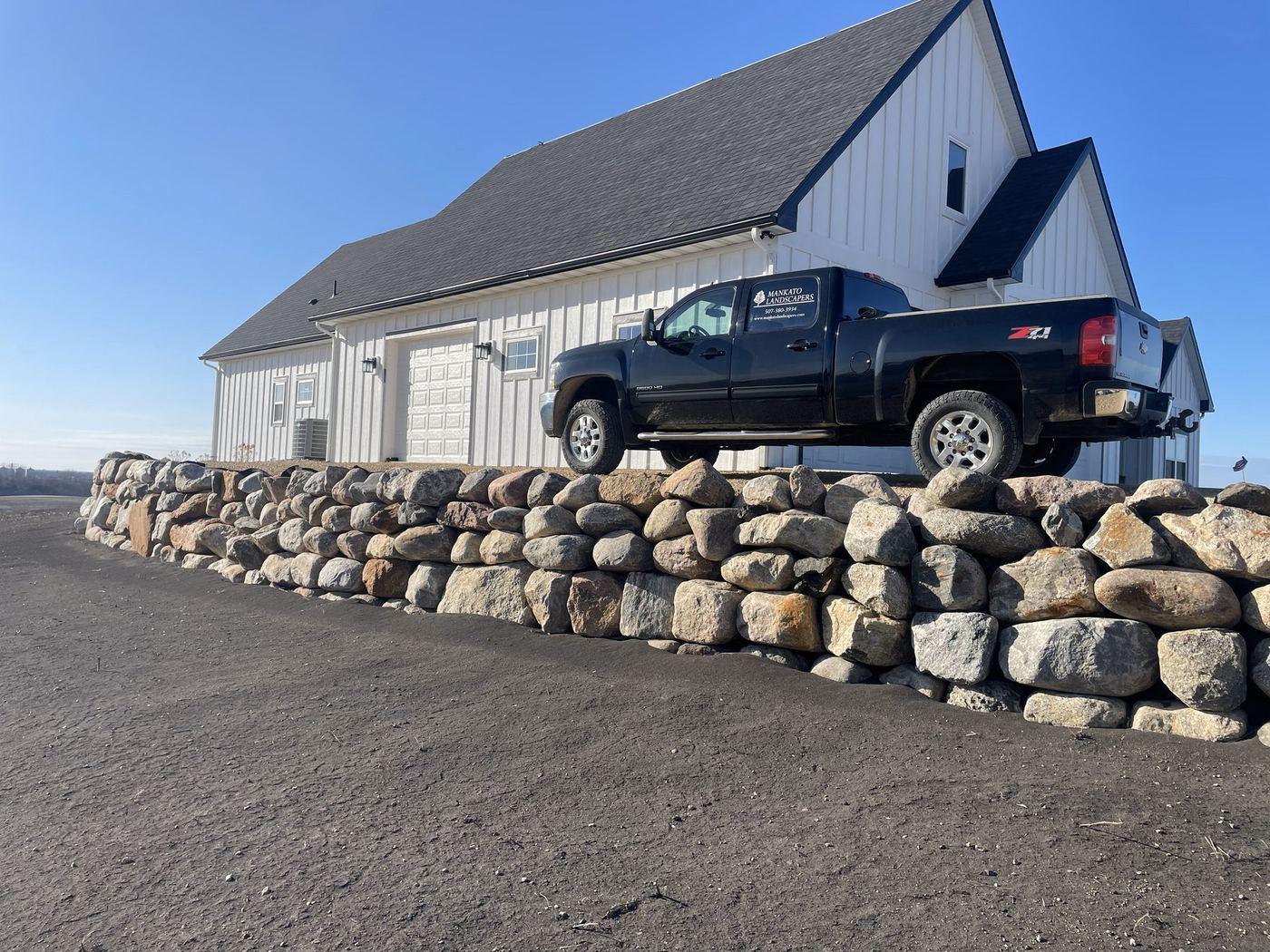 Pickup truck parked above a newly built boulder retaining wall
