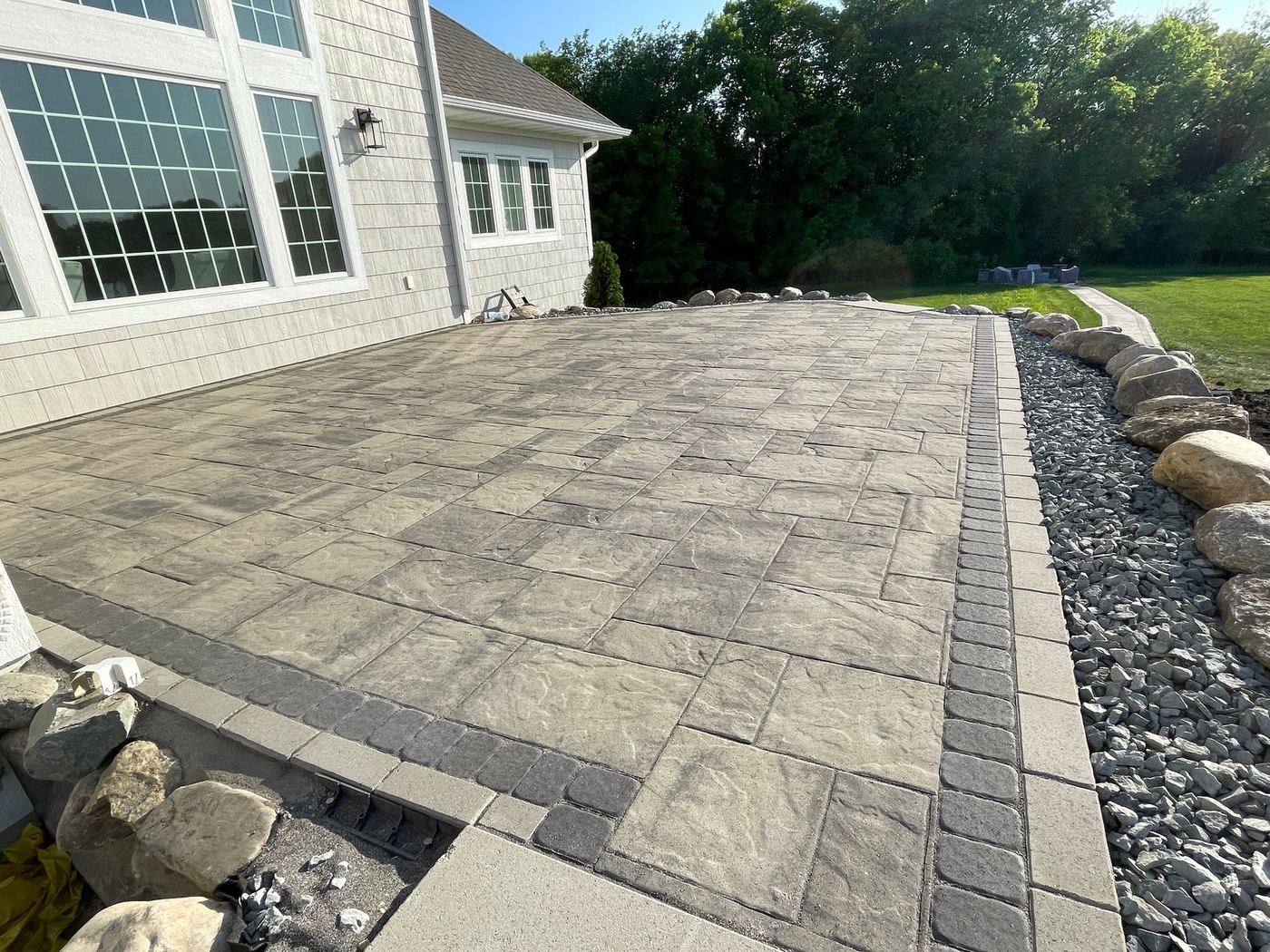 Paver patio with soldier-course border next to a lake home