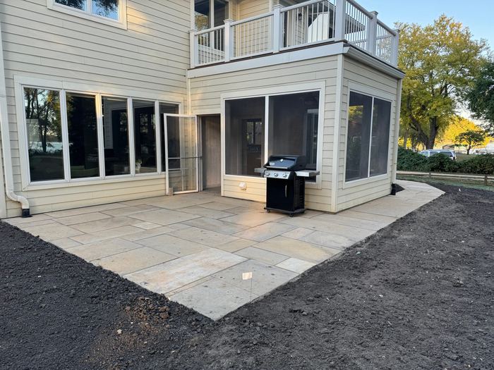 Large stone patio below a screened porch
